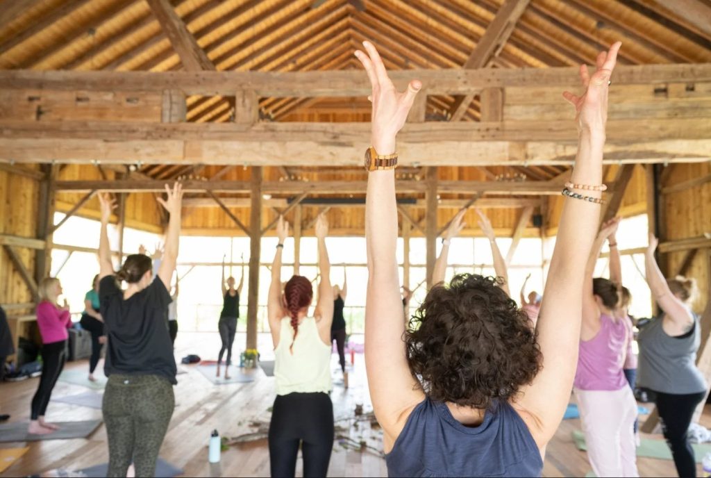 group of people doing yoga in the middle of the barn floor.